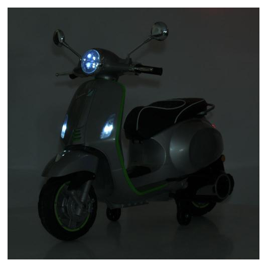 Передняя фара серого скутера Vespa во включенном состоянии ночью